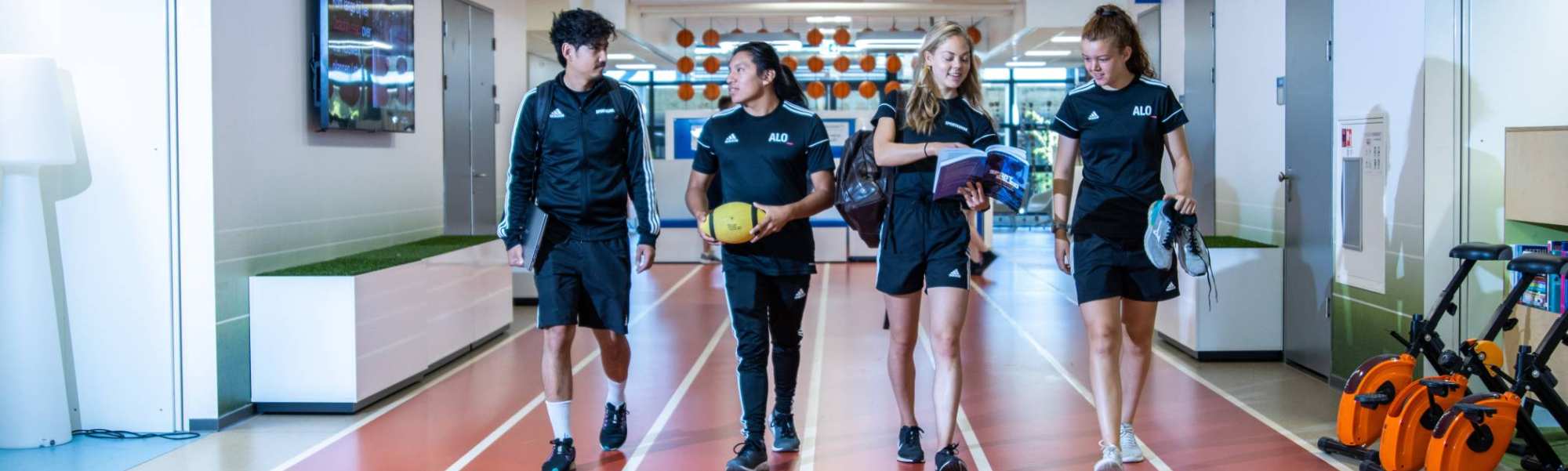 sportkunde en alo samen liggende foto studenten lopen over atletiekbaan binnen bij gymnasion veraf esteban selena carlijn randy 2022
