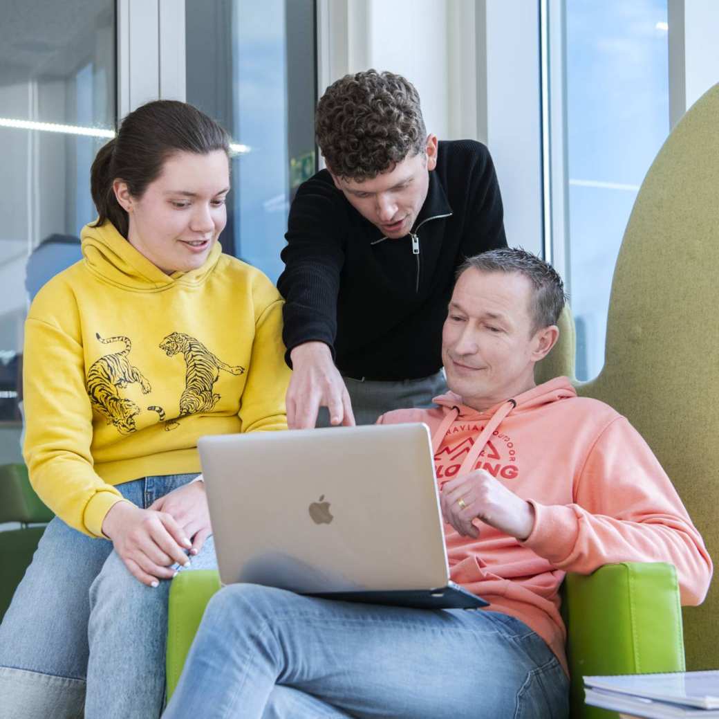 3 masterstudenten zitten bij elkaar en kijken aandachtig naar een laptopscherm