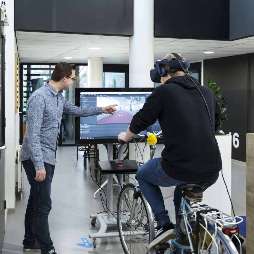studenten doen onderzoek met VR-bril, beeldscherm en fiets