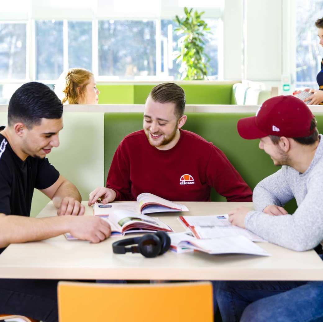 drie studenten van opleidingskunde deeltijd aan een tafel in de HAN campus