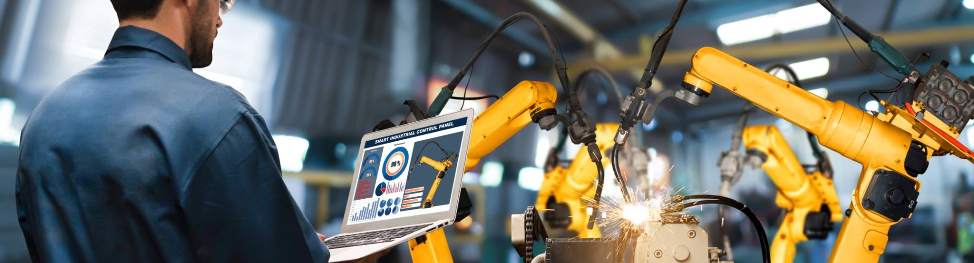 Man met tablet kijkt naar robotarmen in Digitale Fabriek