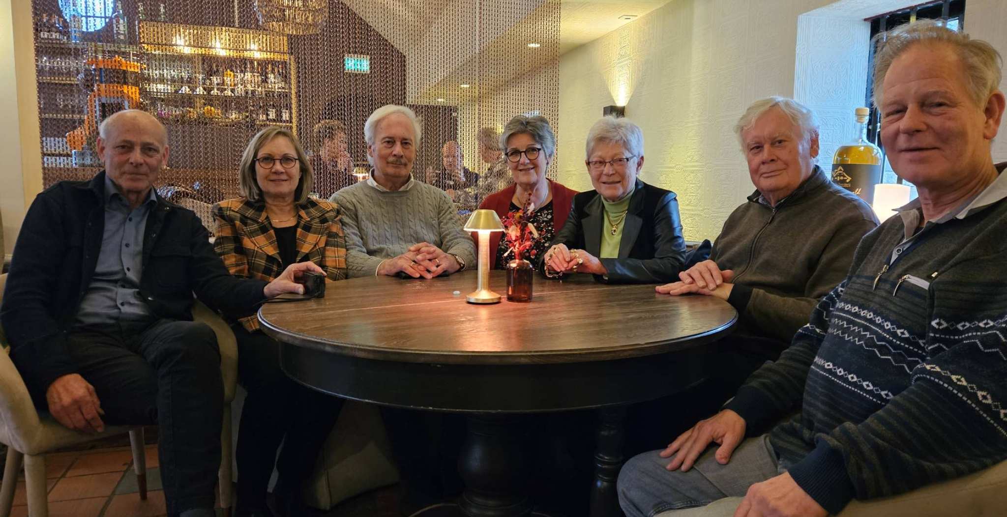 zeven VOM-bestuursleden in restaurant aan ronde tafel