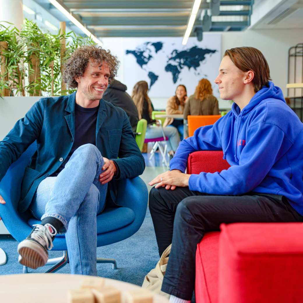 Een student en een docent praten in stoelen in de HAN campus in Nijmegen