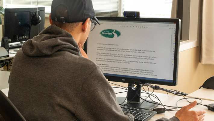Jongen met pet vult een onderzoek naar overheidsteksten in op een computer in het experience lab