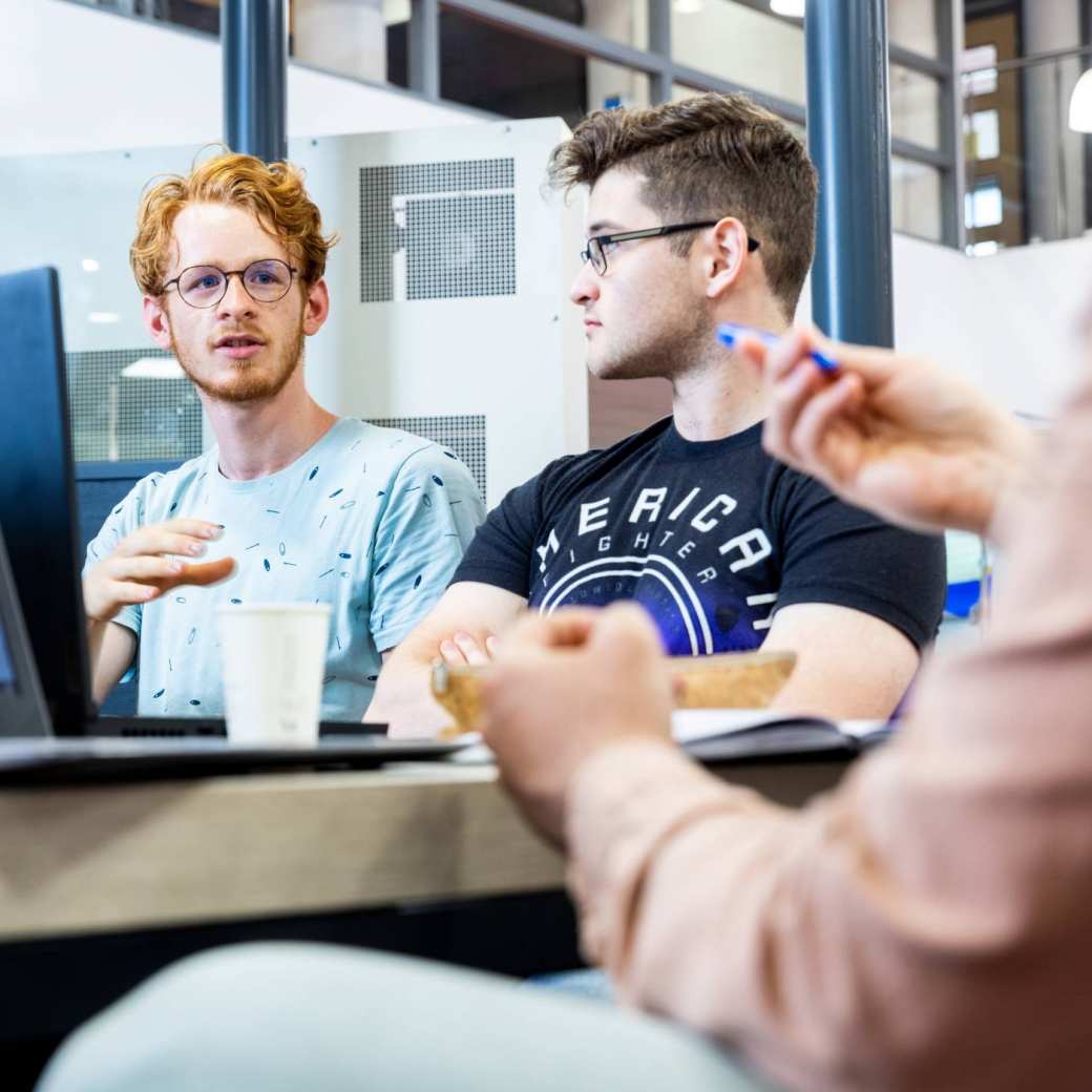 Two Mechanical Engineering students doing group work behind laptops - Werktuigbouwkunde