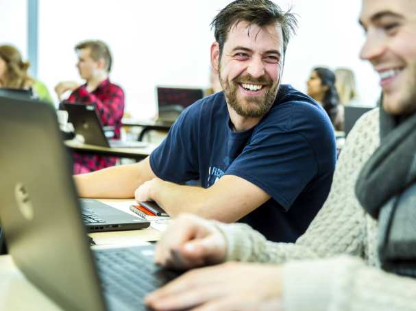 twee studenten lachen met laptop