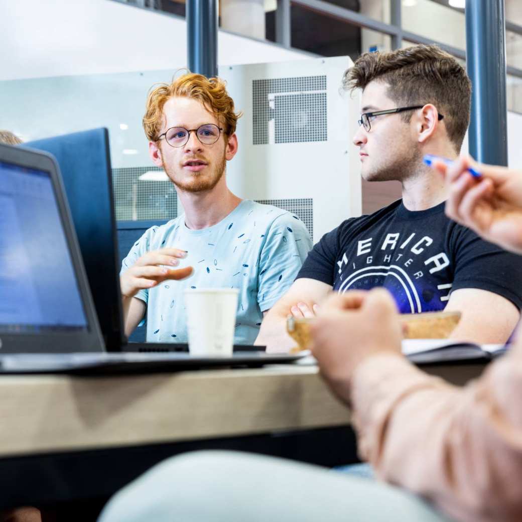 Two Mechanical Engineering students doing group work behind laptops - Werktuigbouwkunde
