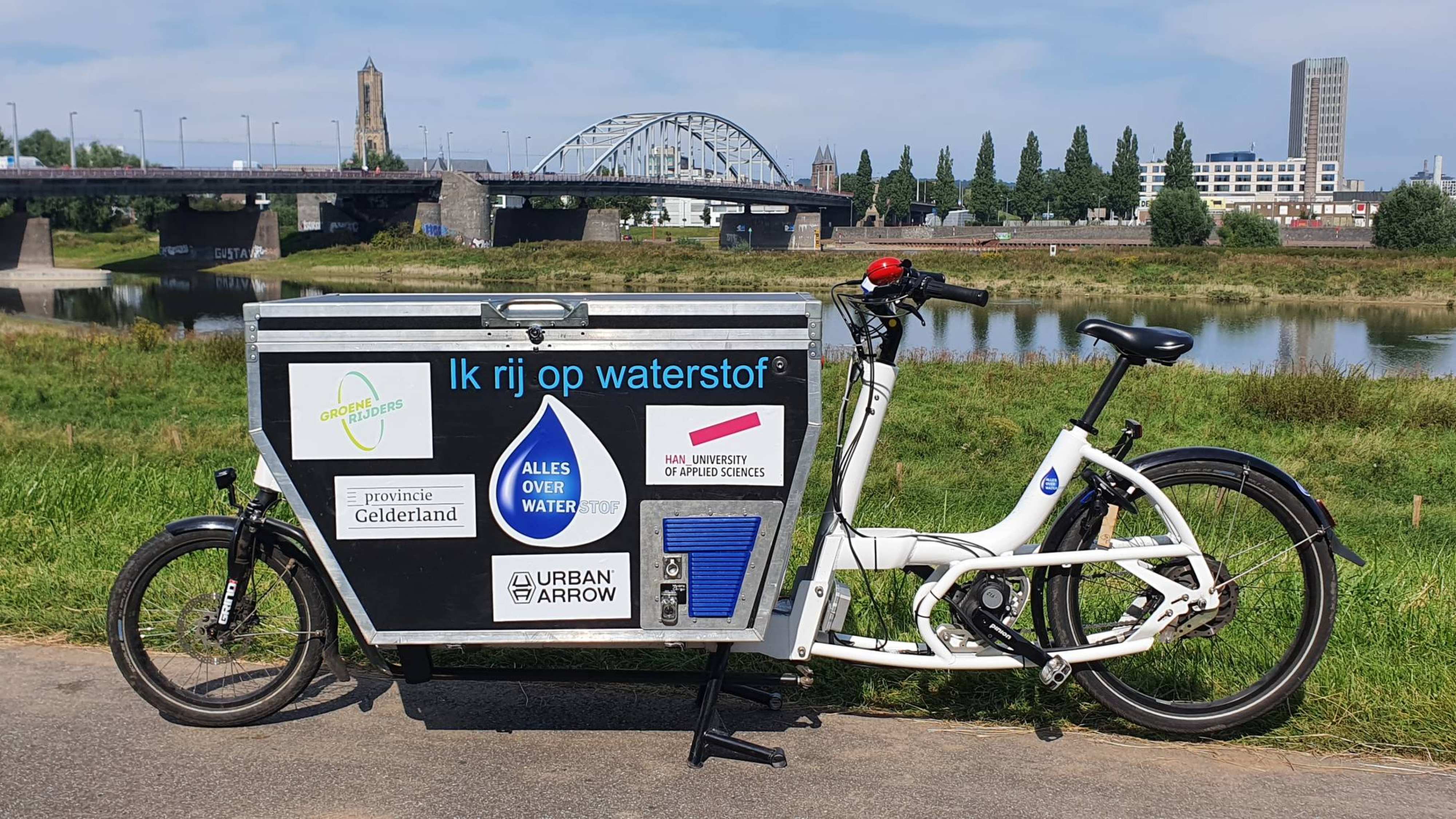 Waterstofbakfiets met natuur, rivier en John Frostbrug Arnhem op de achtergrond