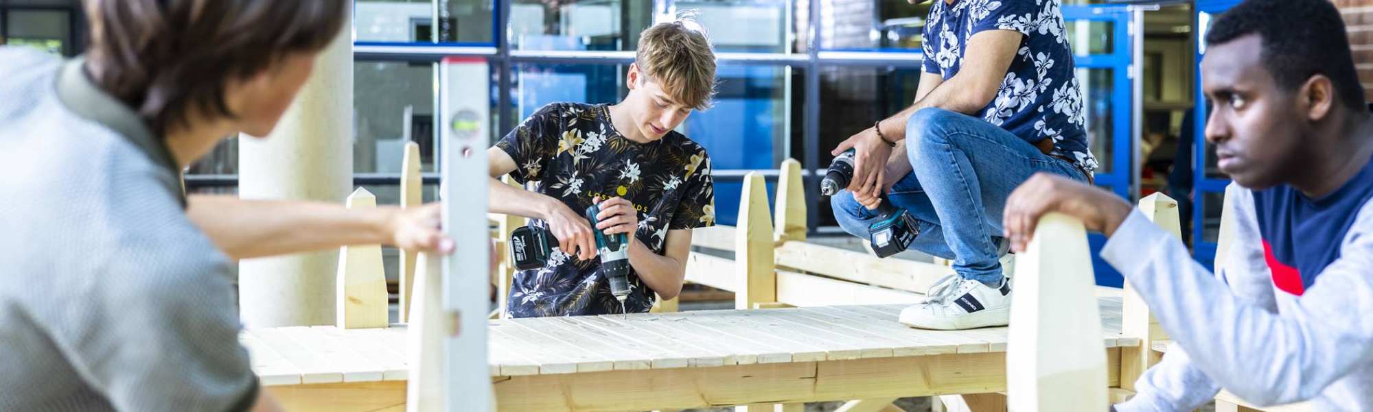 4 studenten civiele werken aan de houten steiger onder het gebouw van de opleiding 