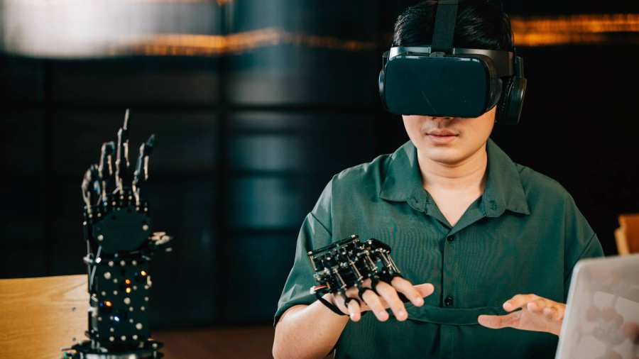 Afbeelding van een jongen met een VR-bril op die een robot hand bestudeert