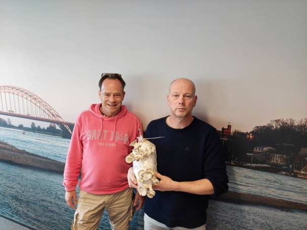 477114 ProcescoÃ¶rdinator Mark Heussen en Ruud Klep van de Versfabriek poseren voor een afbeelding van Nijmegen aan de Waal met een zak waarop oesterzwammen groeien op mengsel met koffiedrab.