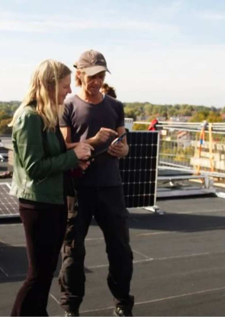 509004 Twee technici overleggen op een dak bij het leggen van zonnepanelen.