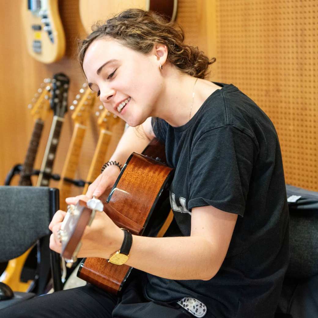 Muziektherapie studente speelt op haar gitaar tijdens een praktijkles