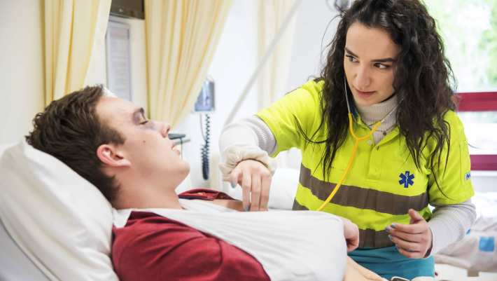 patient met mitella in bed luisteren naar hartslag