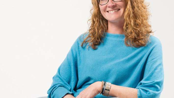 452419 Portretfoto van promovenda Rosa van Doormaal. Zij doet promotieonderzoek bij het project Enactive Mind Autisme. Op de foto heeft ze rood haar, krullen, draagt een bril en zit met blauwe trui in een stoel. 