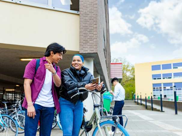 International students Diego and Chadionne with their bikes looking for directions on the Arnhem campus of HAN University of Applied Sciences.