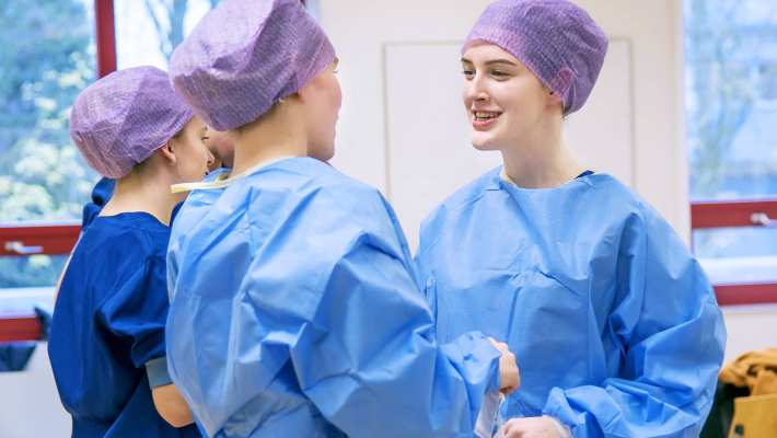 215636 Studenten Medische Hulpverlening in operatiekleding lachen