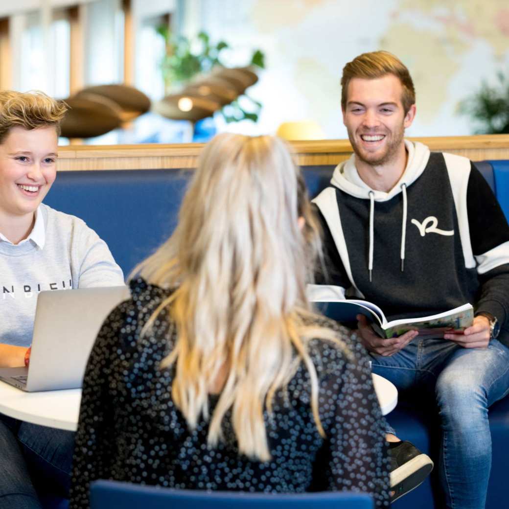 Drie studenten van de HAN Pabo Arnhem zitten bij elkaar en lachen tijdens het studeren.