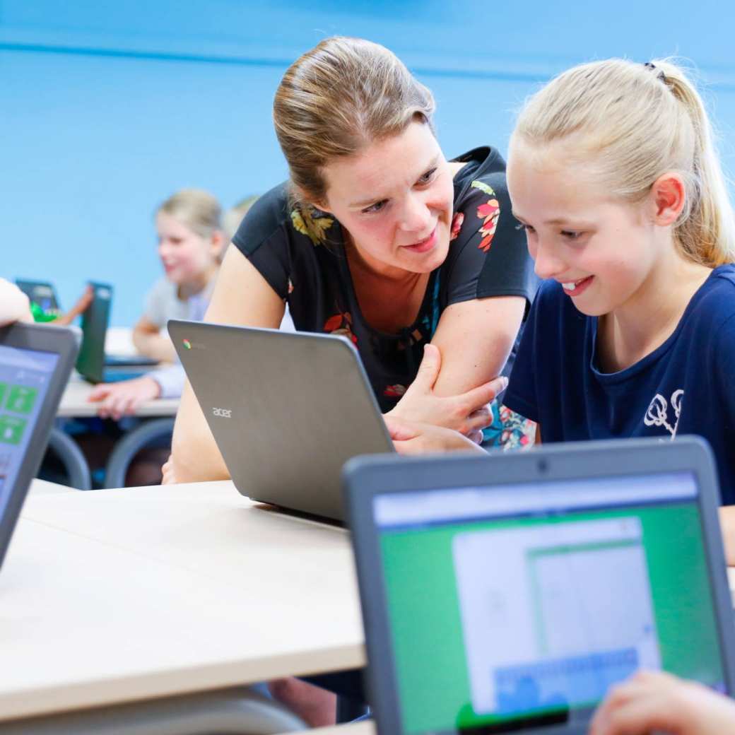 Pabo-docent deeltijd helpt meisje bij laptop.