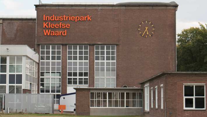 Gebouw op IPKW in Arnhem met klok en oranje letters 