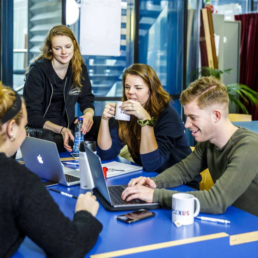 Verpleegkunde studenten drinken samen koffie terwijl ze op hun laptops werken