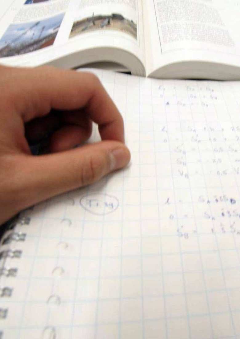 student maakt berekeningen met penen papier