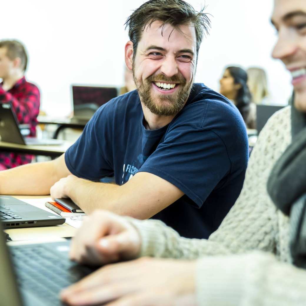 twee studenten lachen met laptop