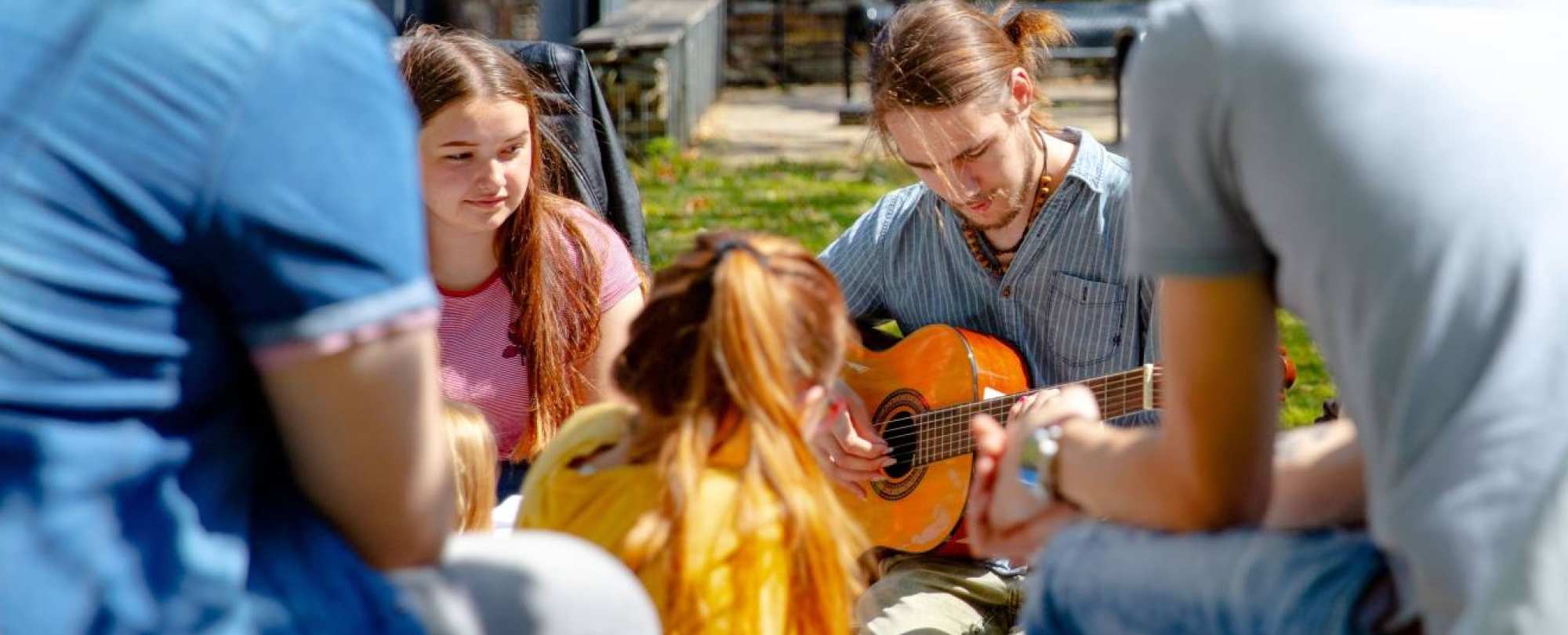 Groep studenten buiten met gitaar
