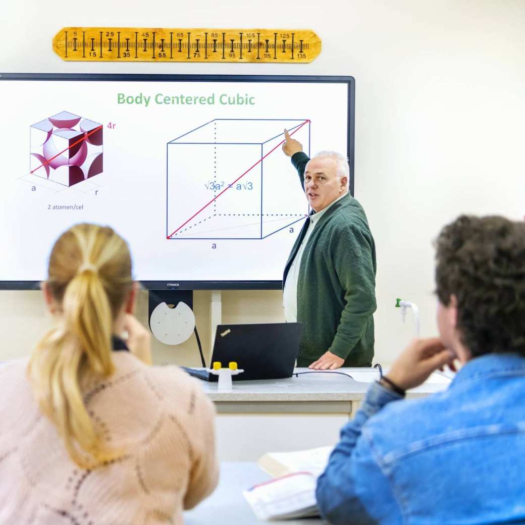 Docent geeft les aan twee studenten Natuurkunde.