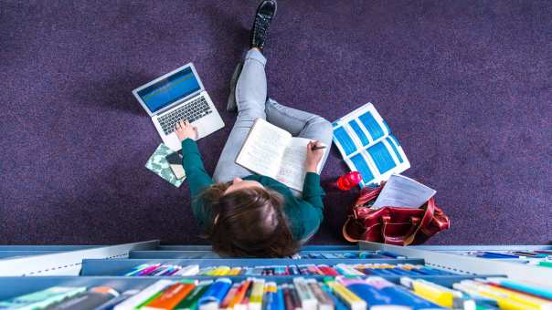 Studente studeren in studiecentrum en werken op laptop, van bovenaf