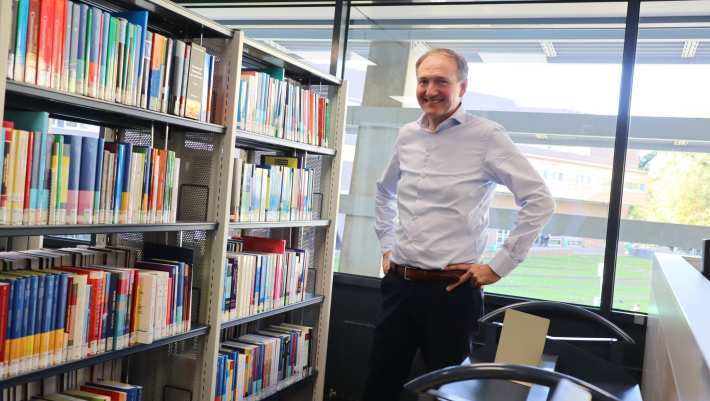 464024 Docent-onderzoeker Ger Sluman staand voor boekenkast in het studiecentrum op Ruitenberglaan 31, na een interview over zijn onderzoek.