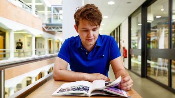 student man leest boeken hal
