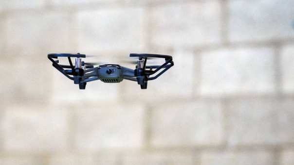 367234 Een drone die door de lucht zweeft met op de achtergrond een stenen muur.