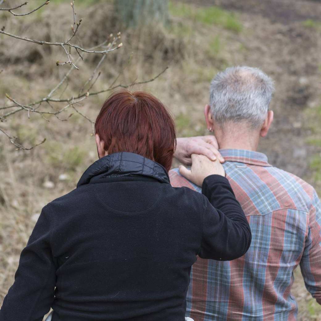 360551 Vrouw steunt man tijdens wandeling in het bos. Sneller Herstel. Helpende hand.