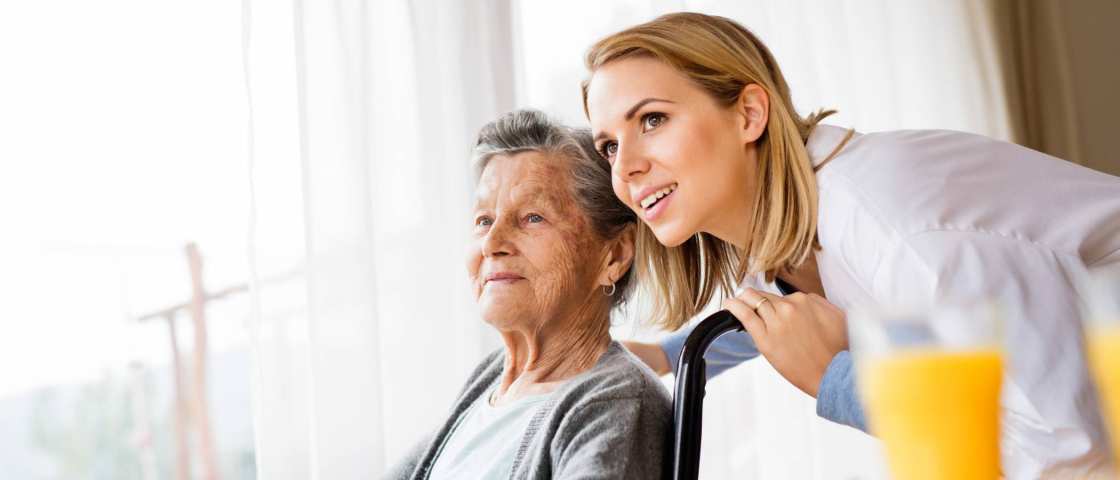 verpleegster in gesprek met een oudere vrouw in een rolstoel