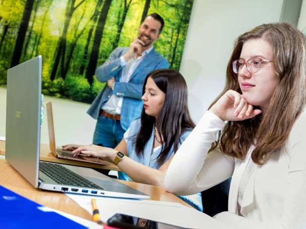 Studenten HAN Pabo Arnhem kijken aandachtig naar laptop. Hun docent kijkt lachend toe.