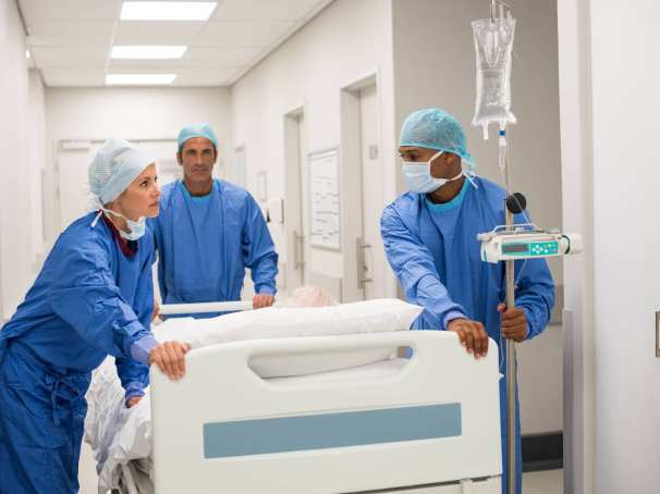 347057 Ziekenhuispersoneel in ziekenhuis duwen een bed met patient