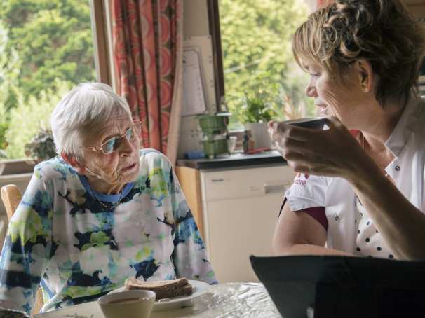 102281 een thuiszorgverpleegkundige helpt een nog thuiswonende oudere dame met beginnende dementie bij de dagelijkse zorgtaken