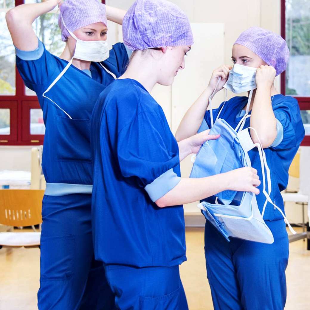 Studenten Medische Hulpverlening trekken operatiekleding aan.