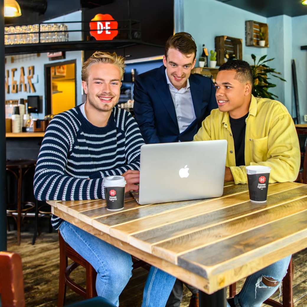drie studenten van bedrijfskunde kijkend naar een laptop