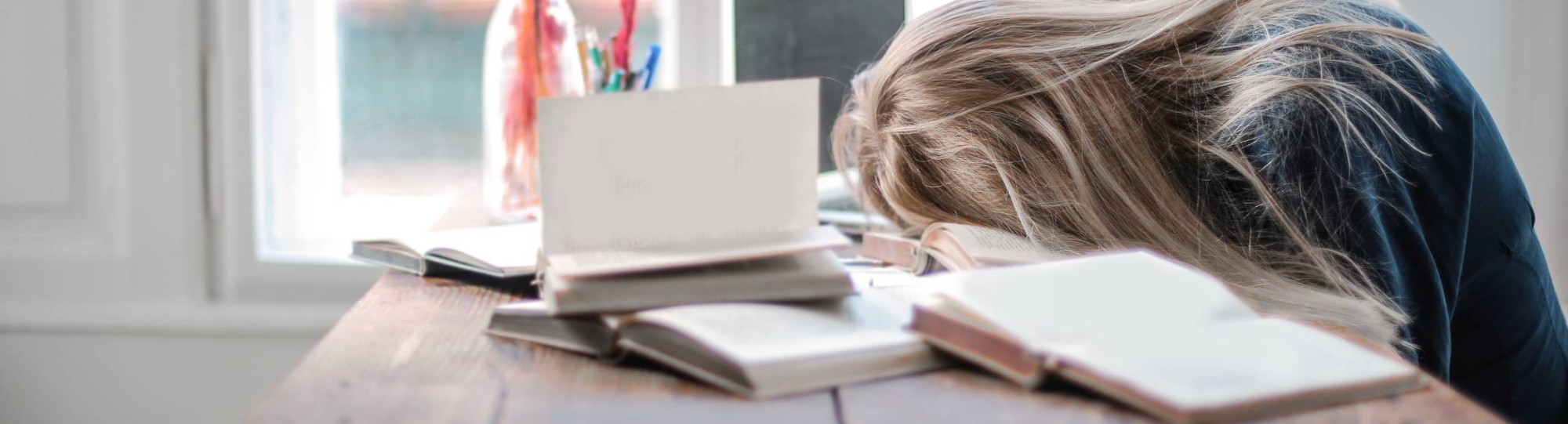 Meisje met lange blonde haren is in slaap gevallen bovenop haar huiswerk