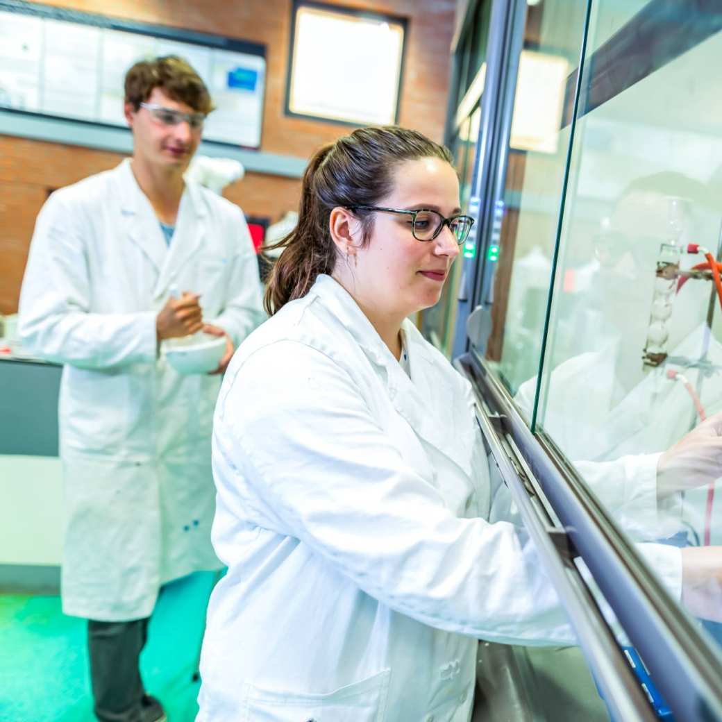 Deeltijdstudenten werken in een laboratorium bij een zuurkast.