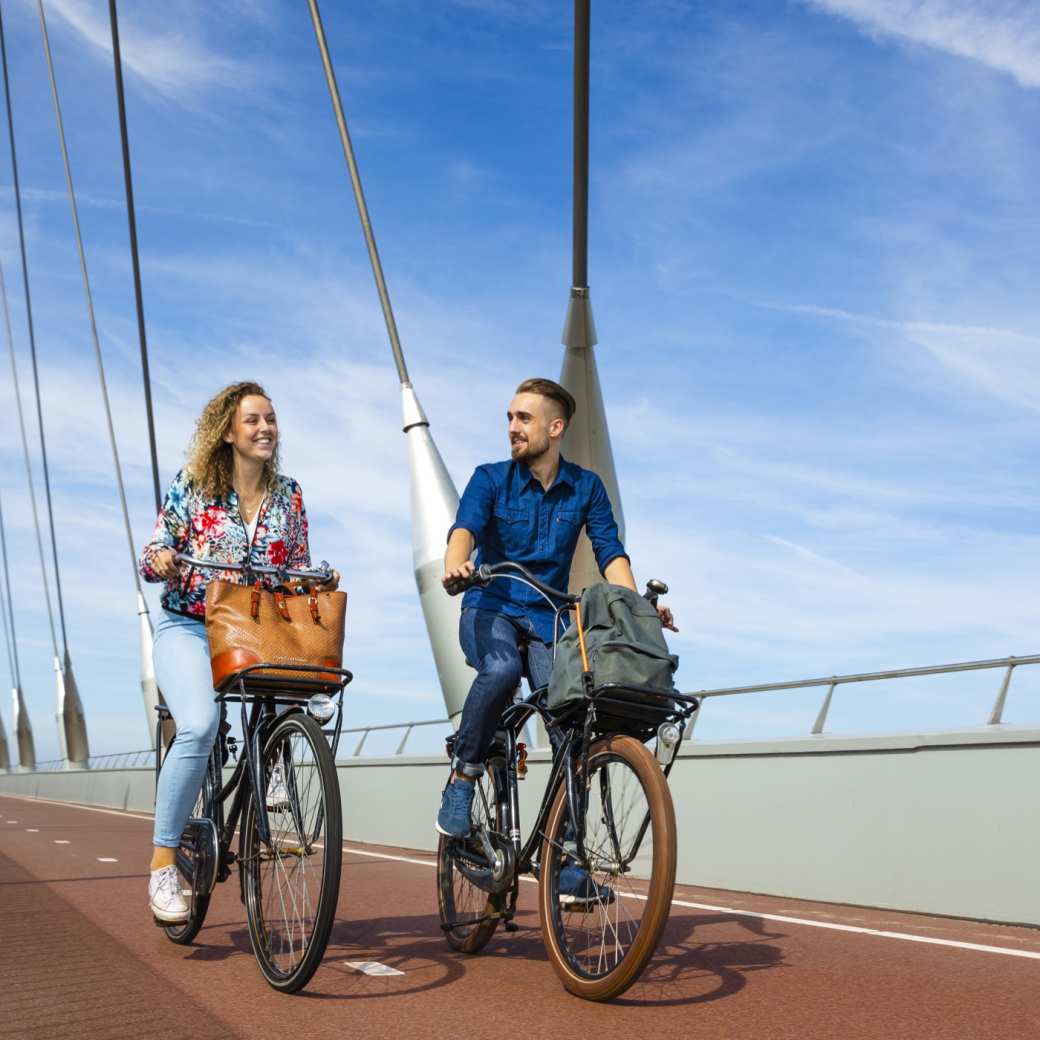 Twee studenten fietsen al kletsend over de brug onderweg naar school.