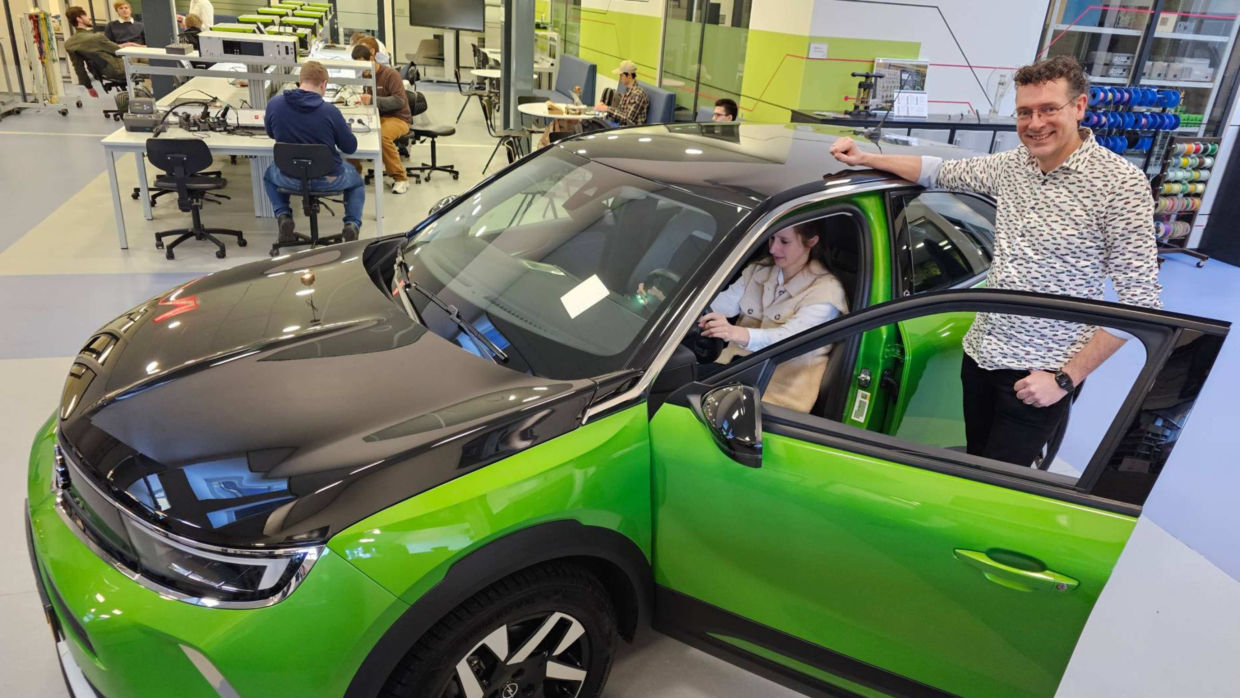 Edwin Kemper (docent) en Selma van Loon (teamleider HAN Automotive) zijn trots op de nieuwe Opel Mokka-e aanwinst. Fotografie: Erik Rijpstra