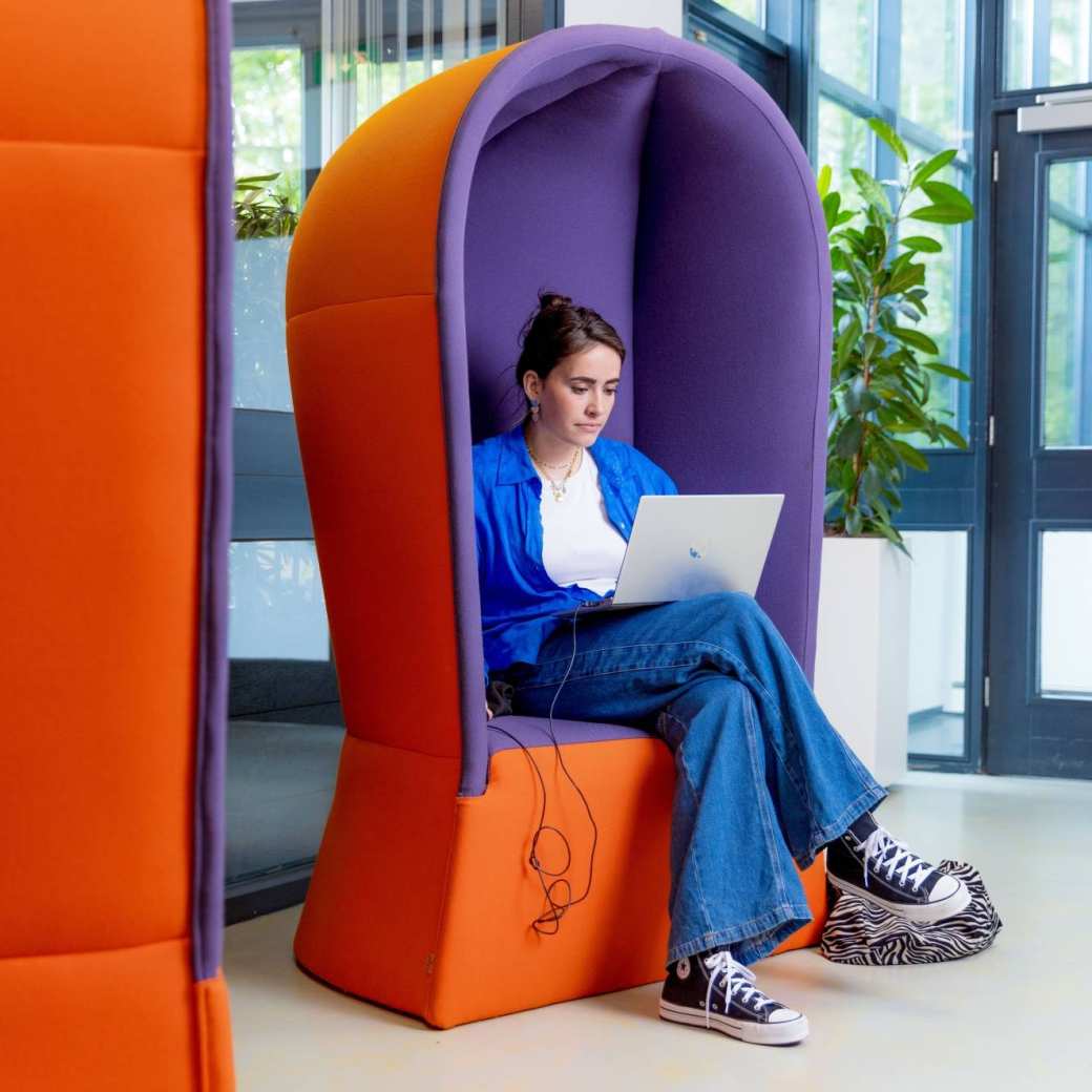 Student op de laptop in een relaxte, geluidwerende stoel op de leslocatie in Arnhem