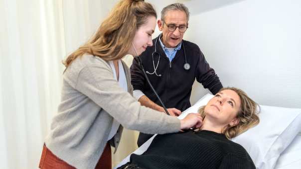 494449 HAN Masterstudent Physician Assistant onderzoekt liggende patiÃ«nt met stethoscoop terwijl docent uitleg geeft