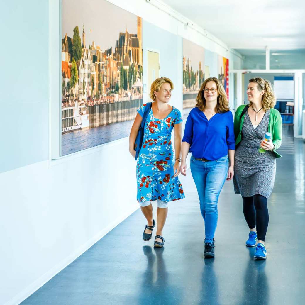 3 masterstudenten lopen samen door de gang op de campus van Nijmegen
