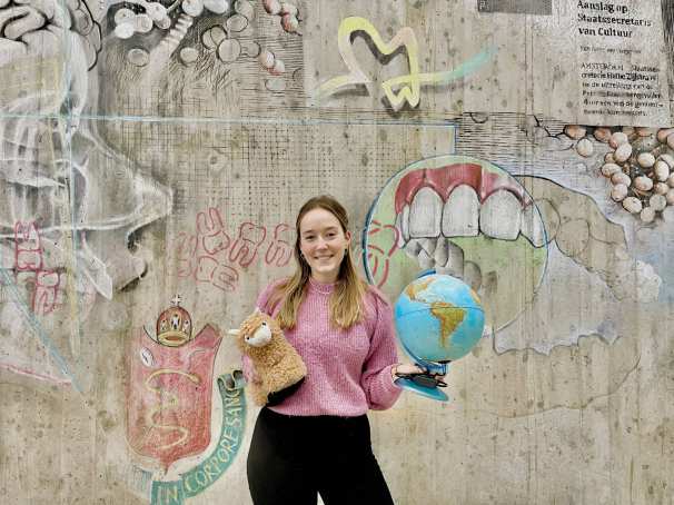 Iris Klein. student Mondzorgkunde met een wereldbol en een knuffel van een lama in haar hand. 