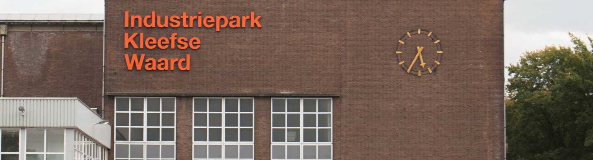 Gebouw op IPKW in Arnhem met klok en oranje letters 