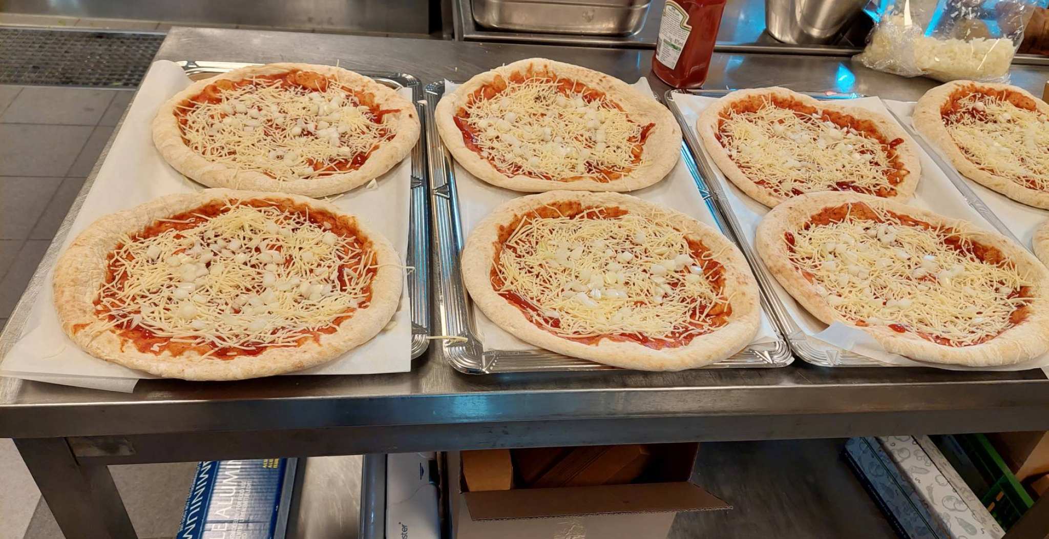 Vers gemaakte pizza's staan klaar om in de oven te gaan in de keuken van het restaurant aan de Kapittelweg Nijmegen